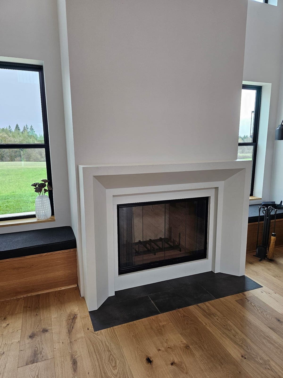Clean-lined modern fireplace surround in cream cast stone with recessed firebox and black tile hearth.
