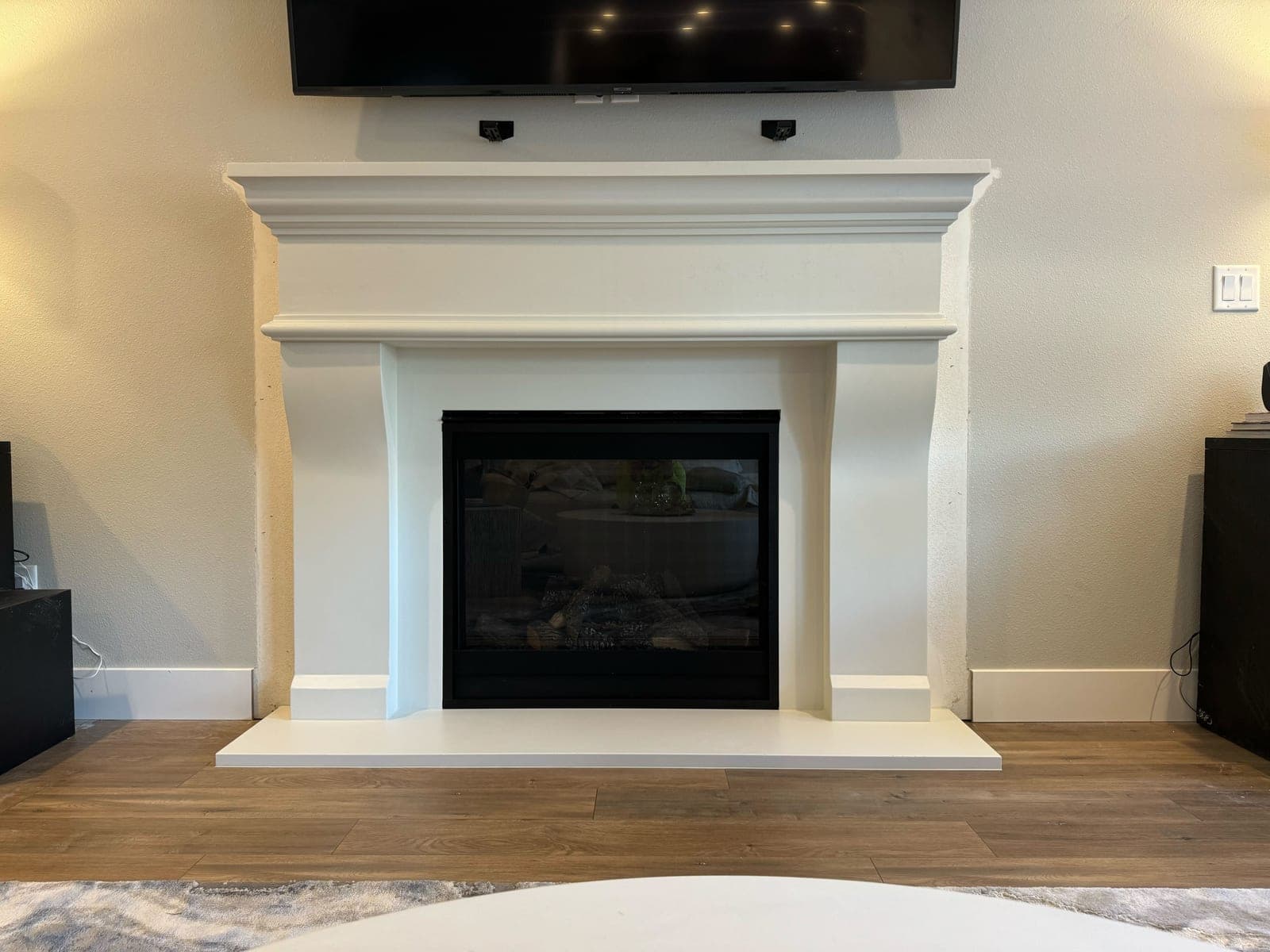 Clean modern fireplace surround in cream cast stone with stepped mantel shelving and black insert.