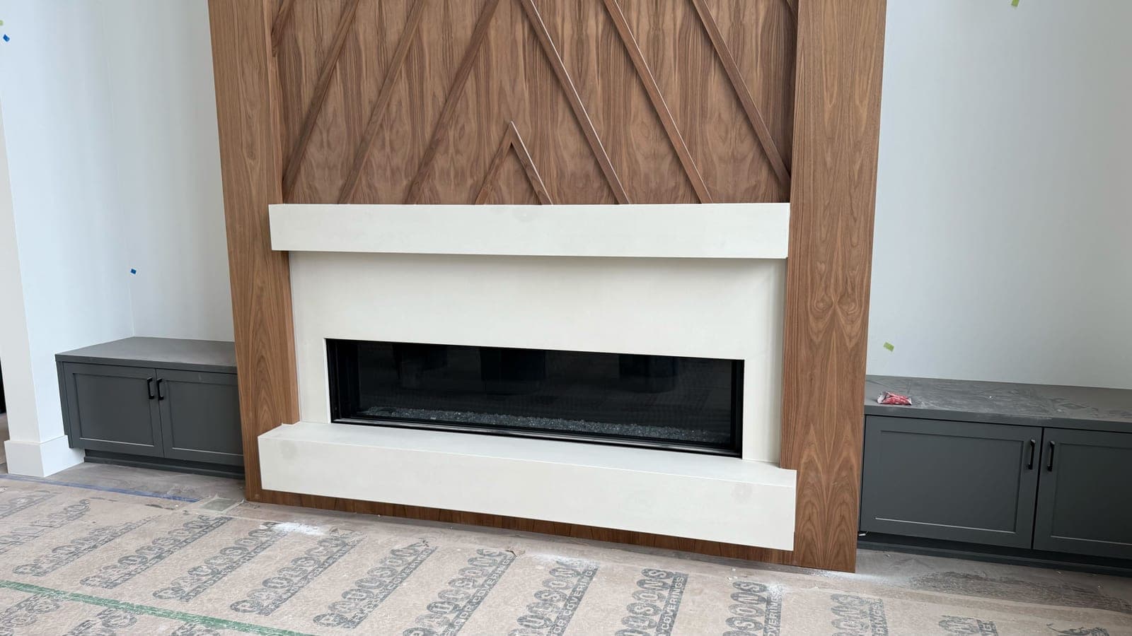 Clean modern fireplace surround with minimalist white cast stone and linear fireplace insert framed by warm wood accent wall.