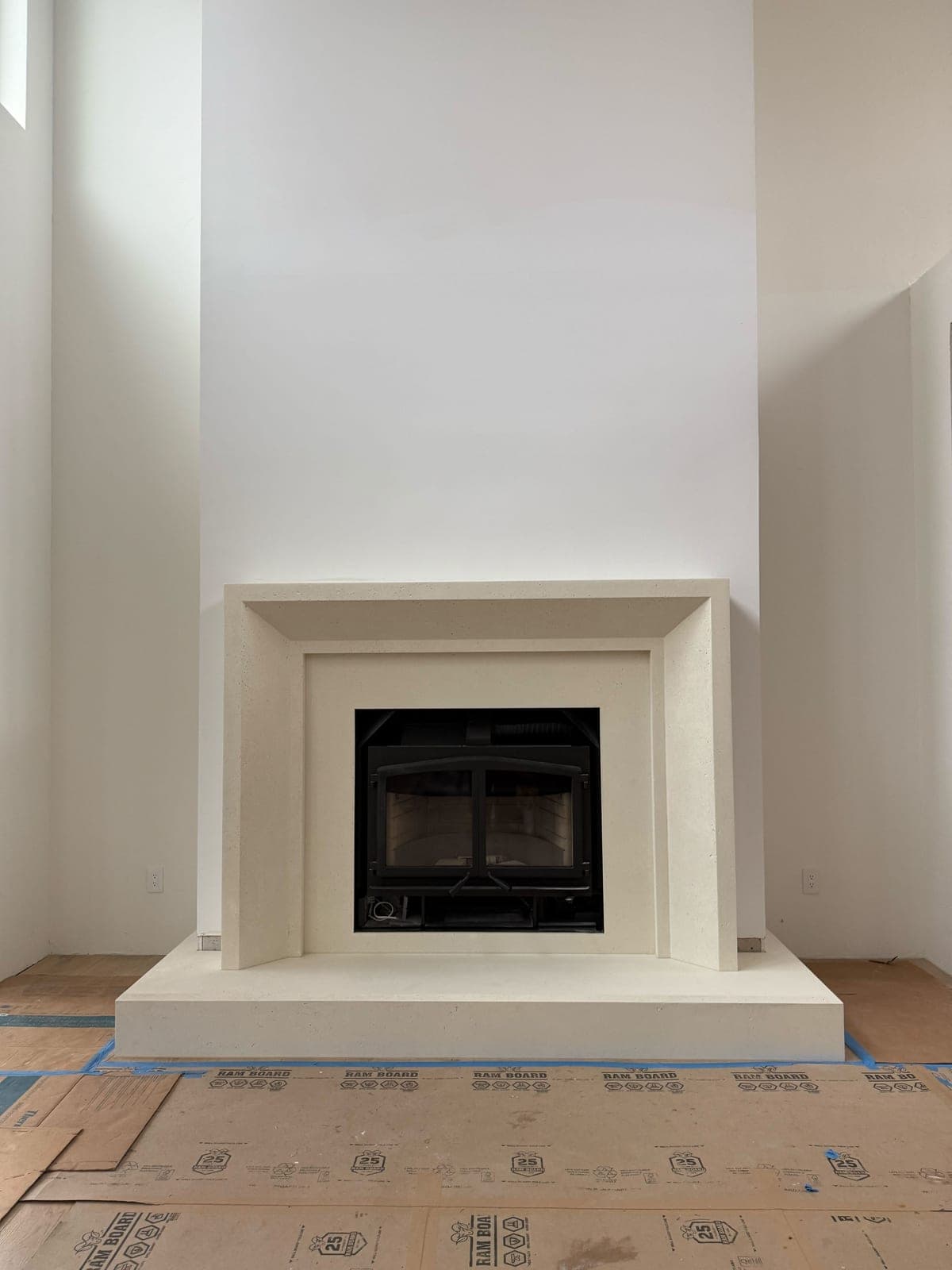 Minimalist cast-stone fireplace surround with clean lines and stepped molding in warm cream finish.