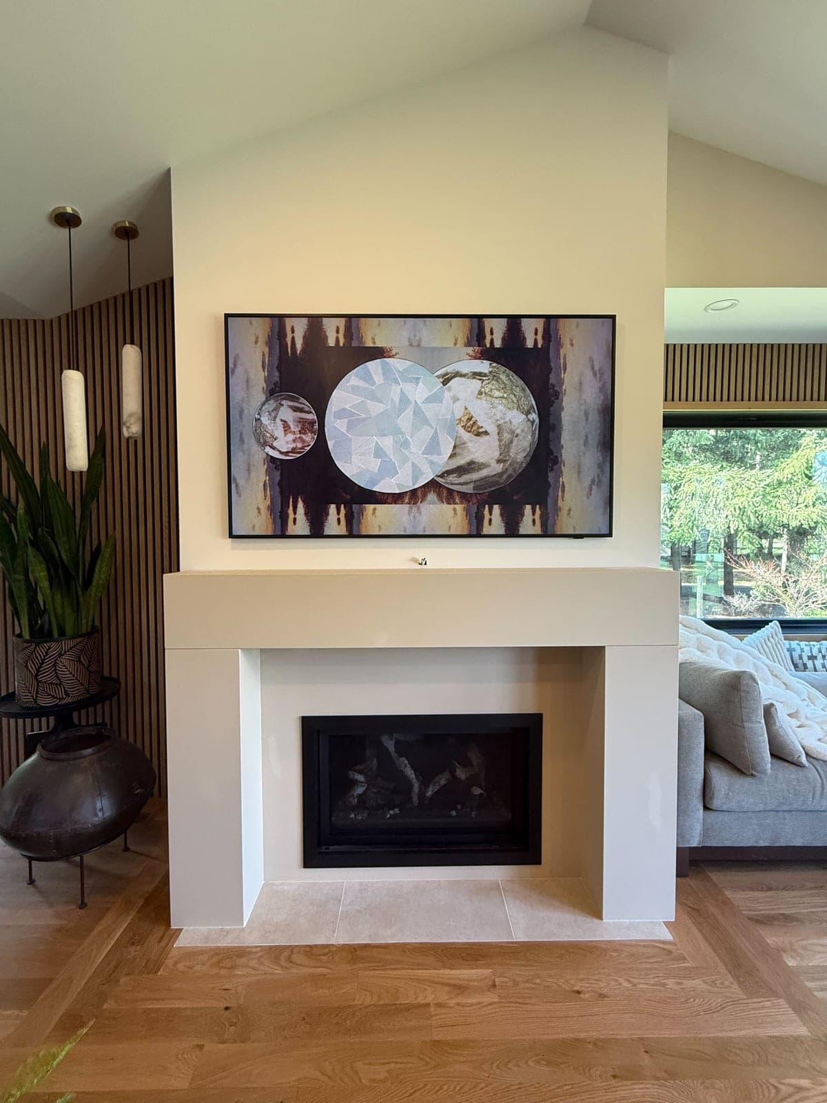 Clean modern fireplace surround with minimalist profile and warm cream finish in bright living space.