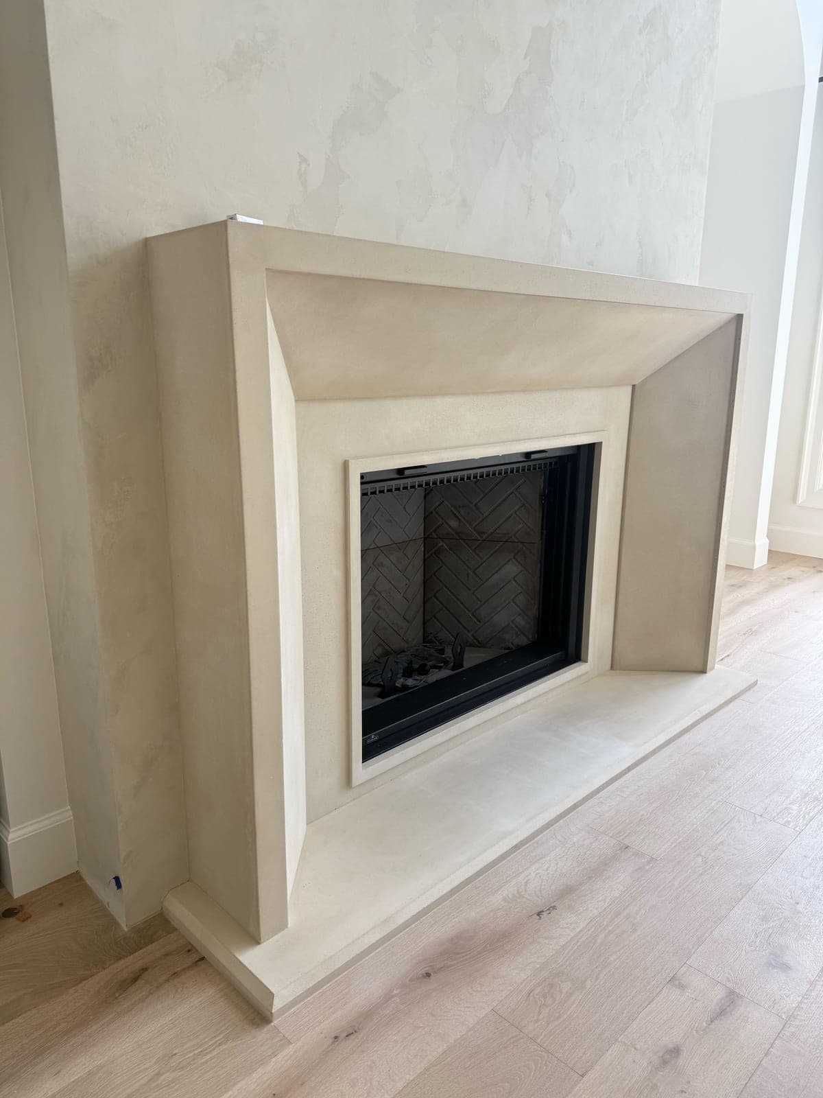 Clean modern cast-stone surround with minimalist profile and cream finish in contemporary living space.