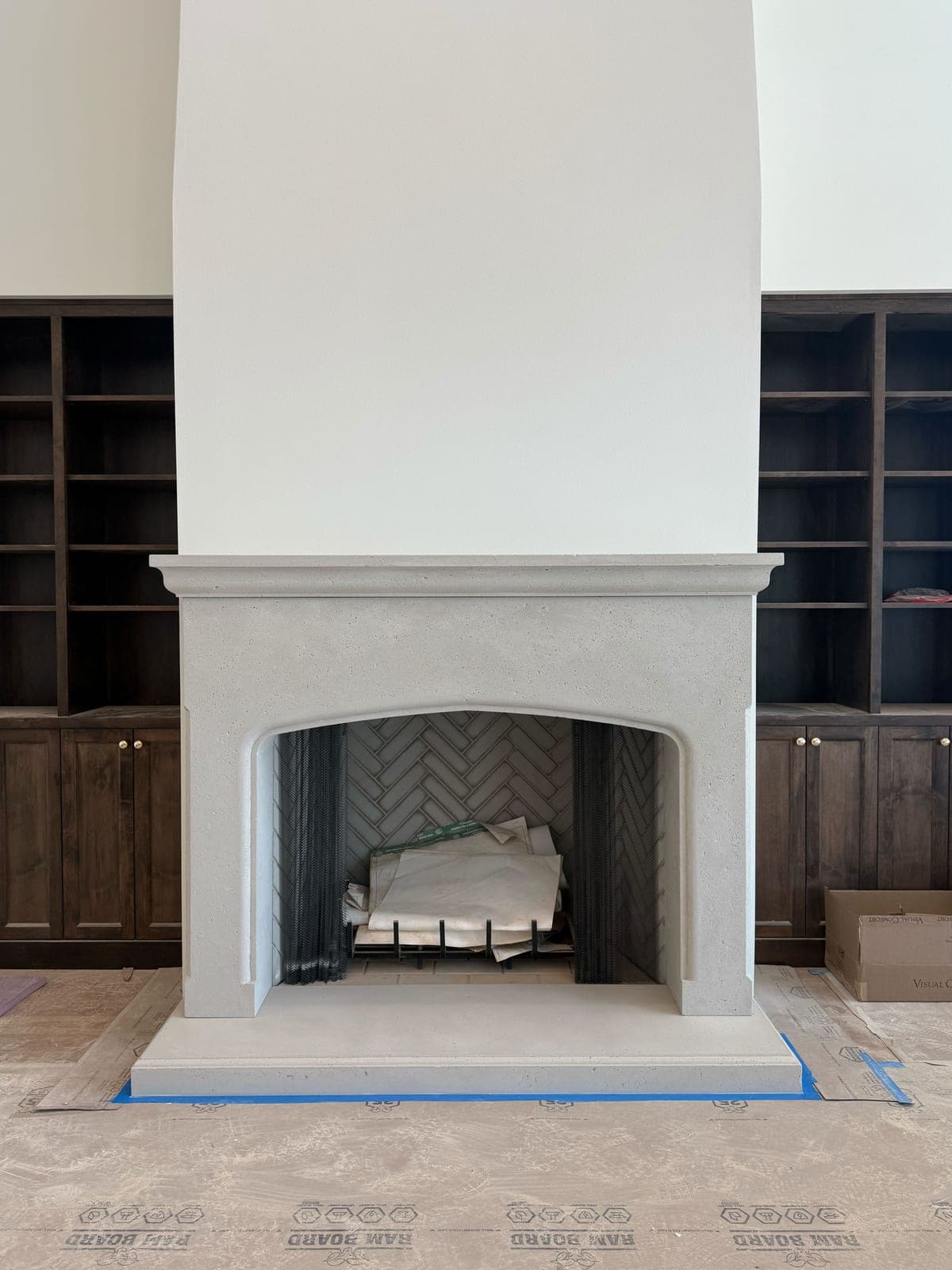 Minimalist cast-stone fireplace surround with clean lines and arched opening in bright great room.