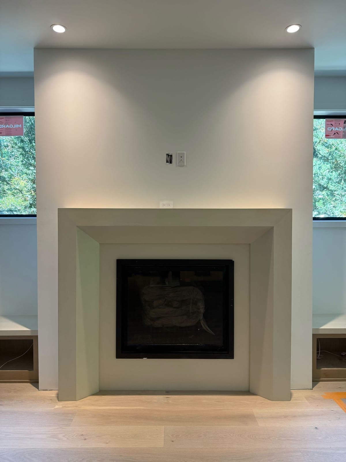 Minimalist modern fireplace surround with clean recessed design and integrated TV niche in cream cast stone.