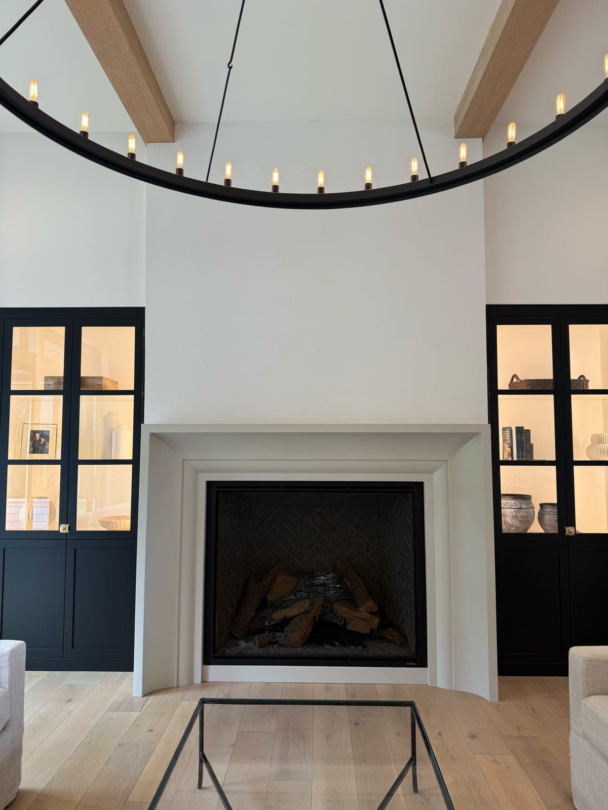 Clean modern fireplace surround with minimalist profile in cream stone, integrated into contemporary great room.