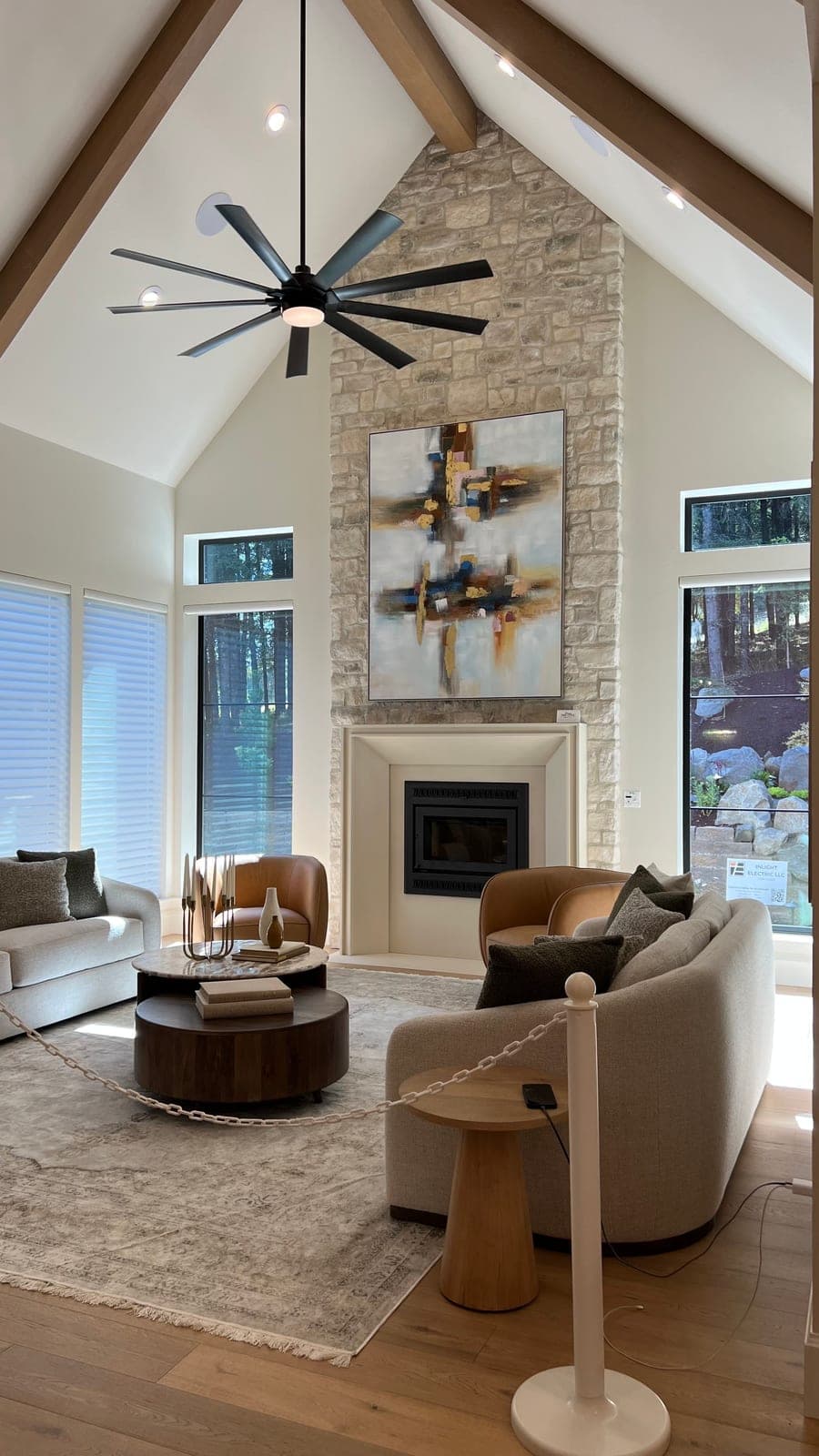 Modern fireplace surround in cream cast stone anchors a soaring great room with warm furnishings and forest views.