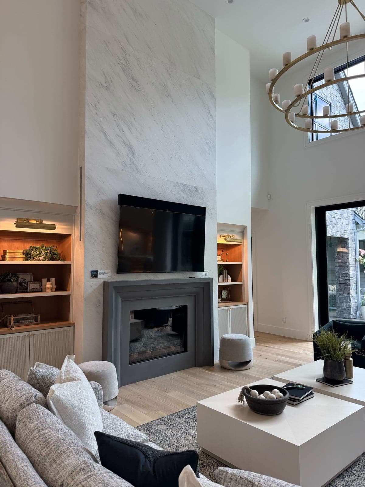 Modern fireplace surround with clean lines, charcoal frame, white marble backdrop in open great room.