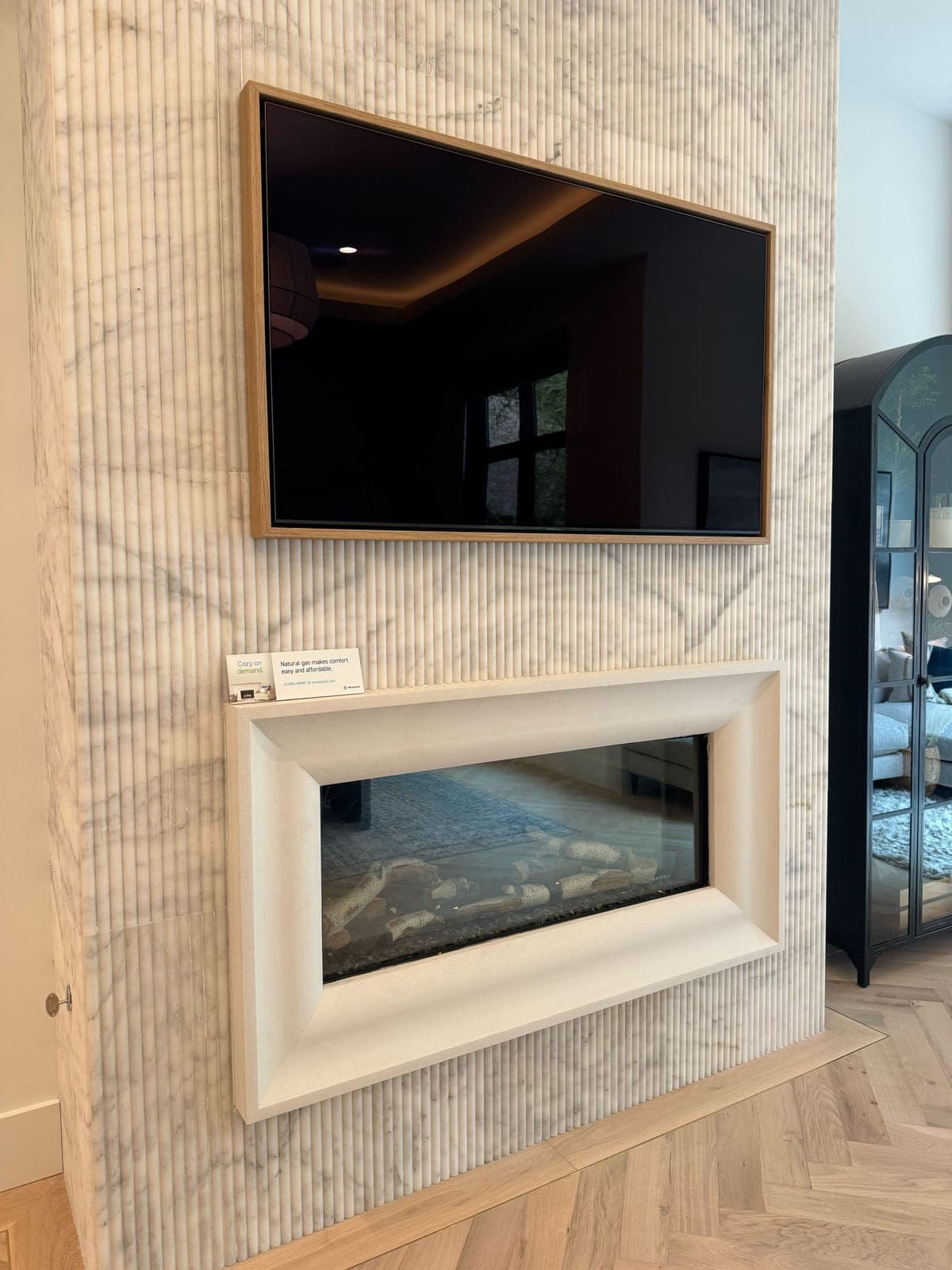 Clean-lined modern fireplace surround with horizontal linear texture backdrop and integrated TV above.