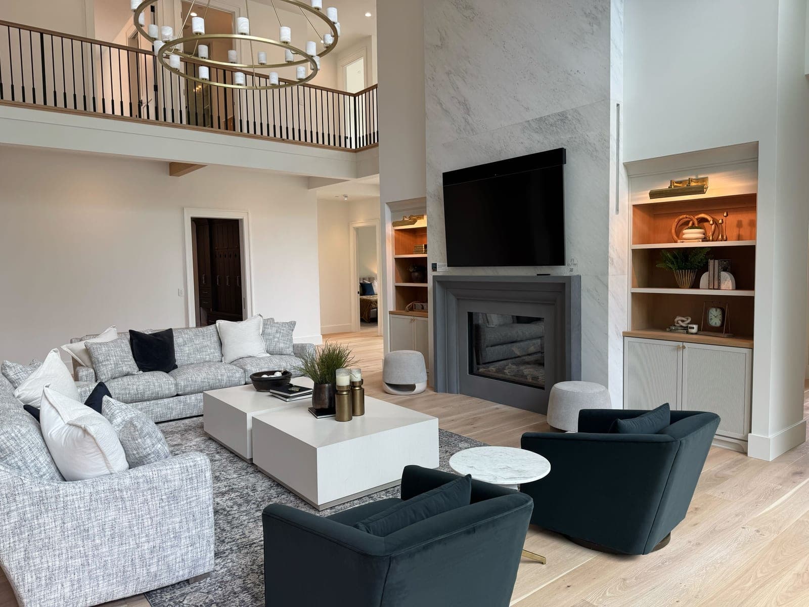 Modern two-story great room with charcoal fireplace surround, marble accent wall, and contemporary furnishings.