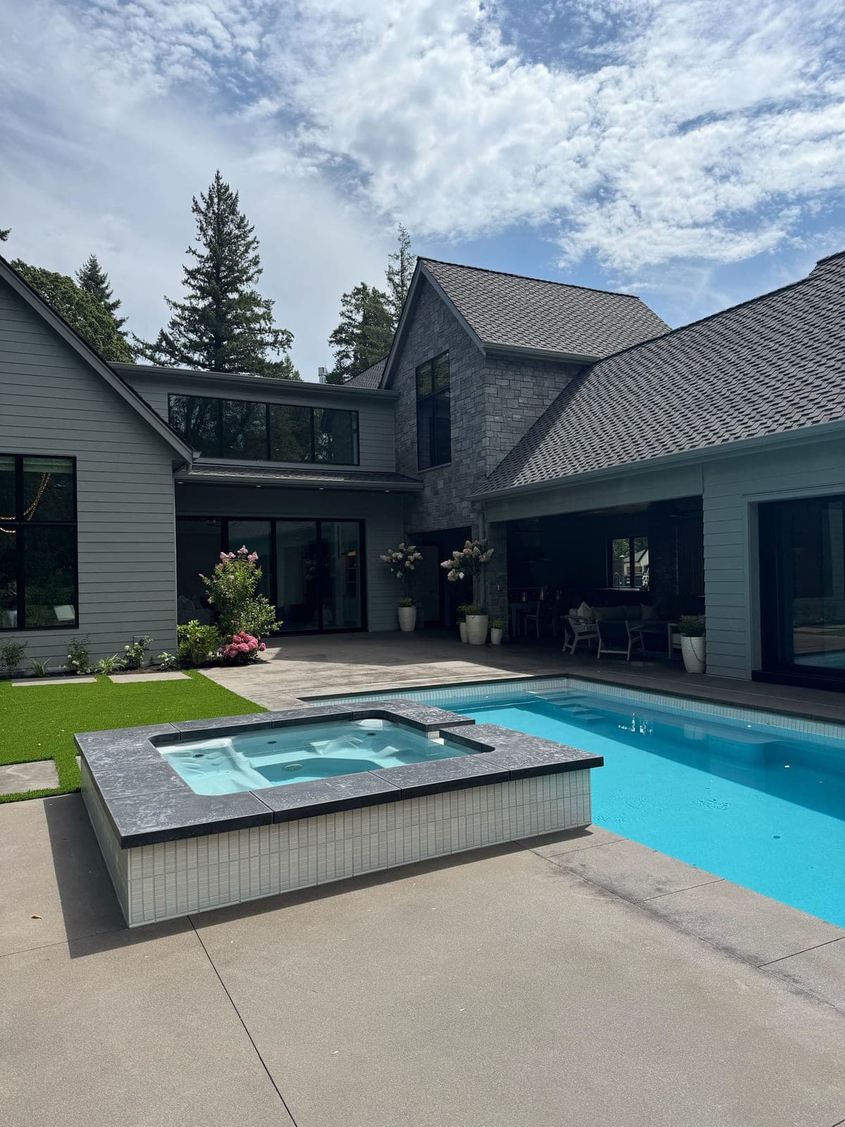 Modern outdoor pool and spa courtyard with contemporary home architecture, no fireplace visible.
