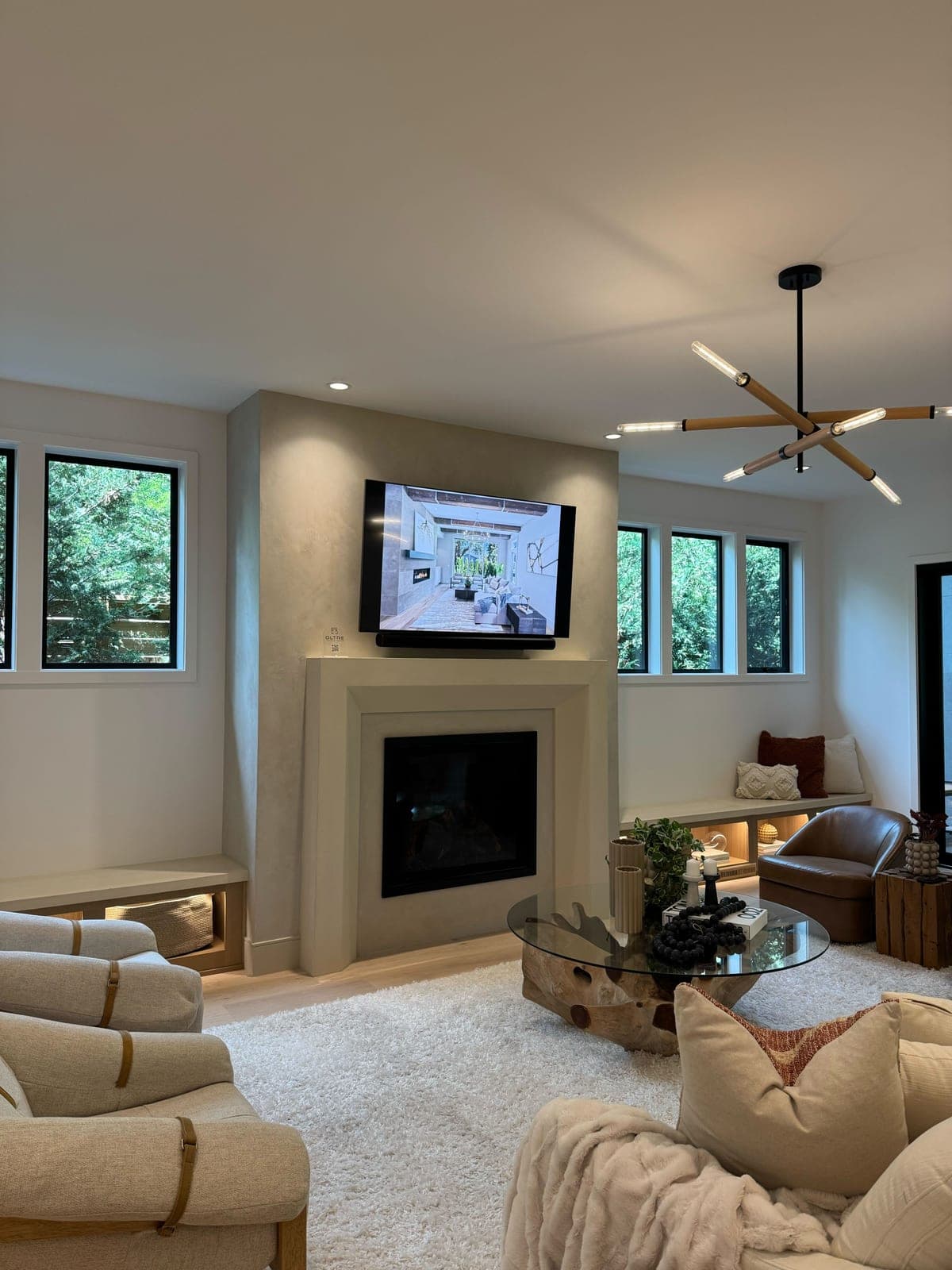 Clean-lined cast stone fireplace surround with minimalist profile in cream finish, anchoring a contemporary great room with media above.