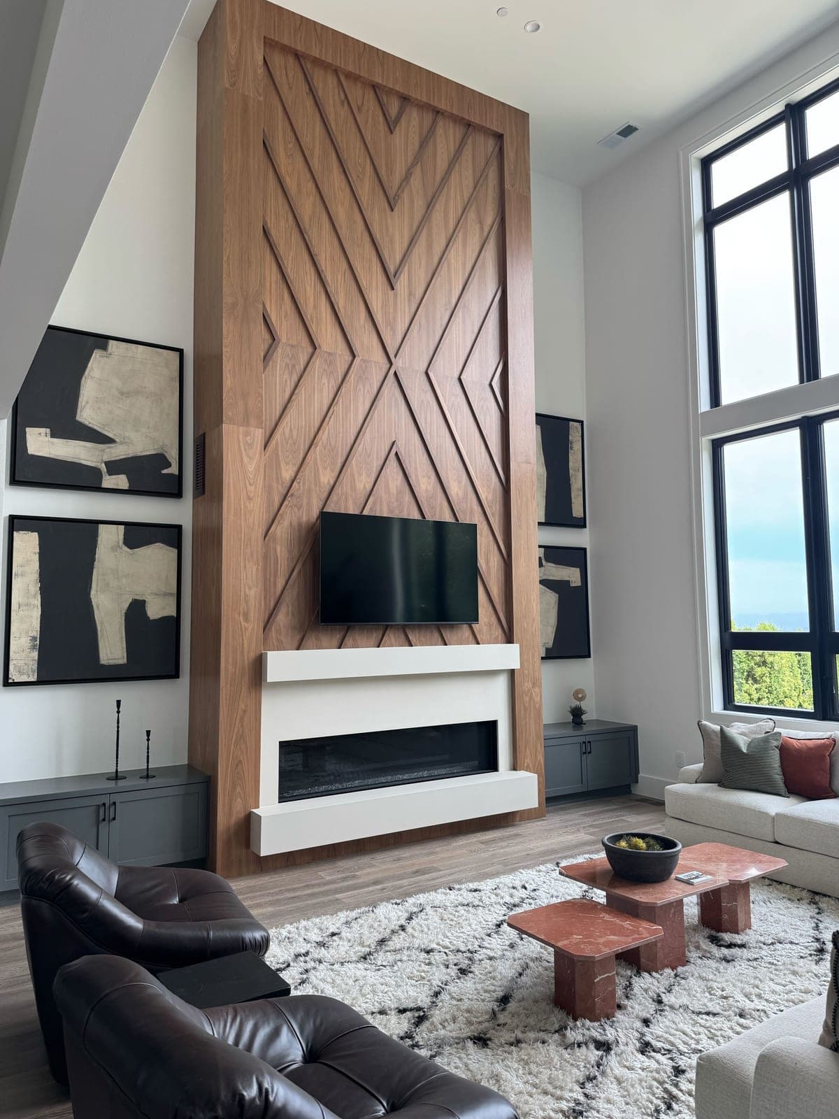 Floor-to-ceiling modern fireplace with geometric wood cladding and linear insert in contemporary great room.