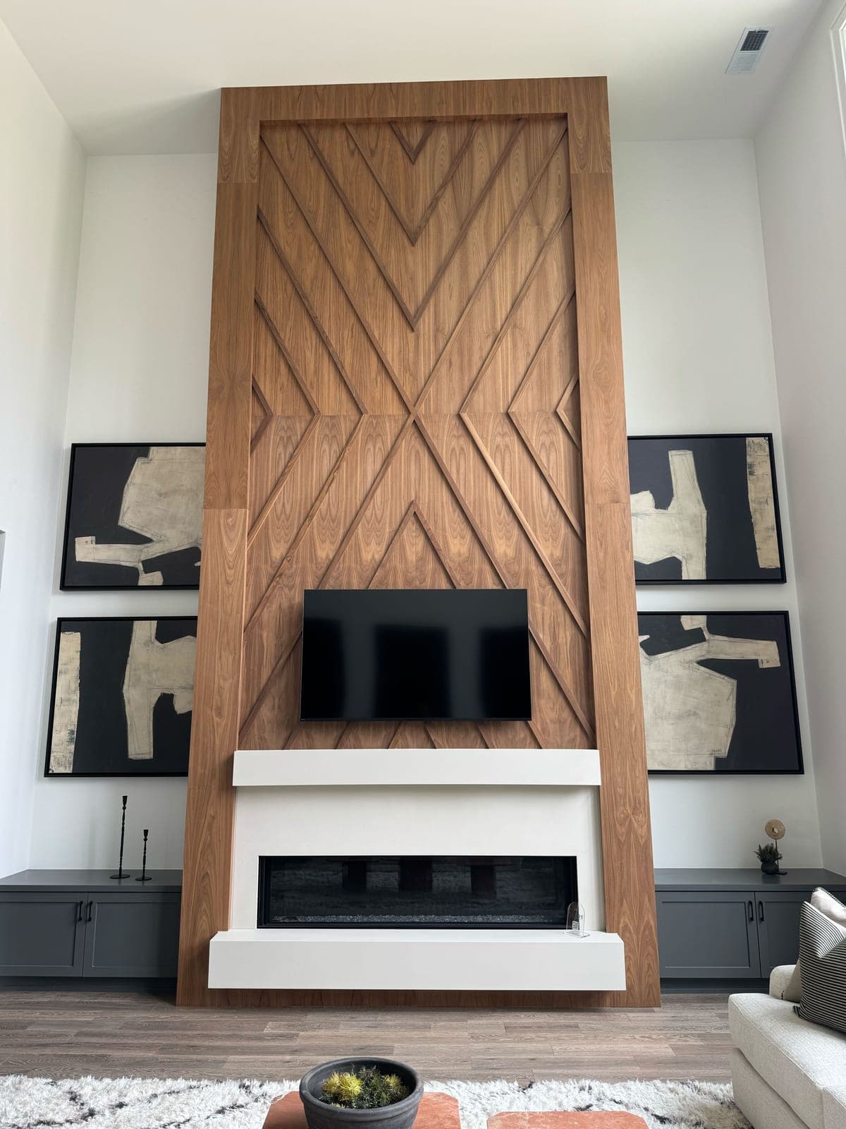 Floor-to-ceiling modern wood-clad fireplace with geometric herringbone pattern and linear gas insert.