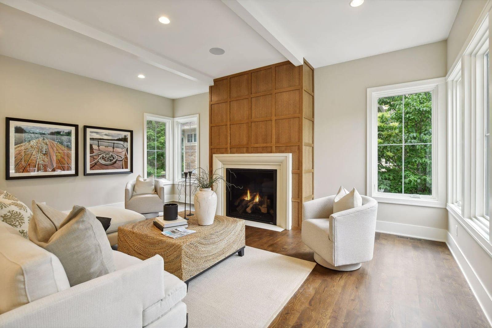 Minimalist cream cast-stone surround with clean lines anchors transitional great room with wood accent wall.