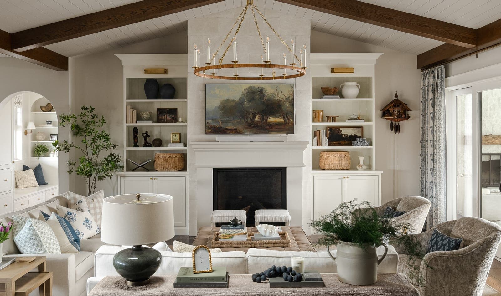 Elegant transitional great room with cream cast-stone fireplace surround, built-in shelving, and sophisticated furnishings.