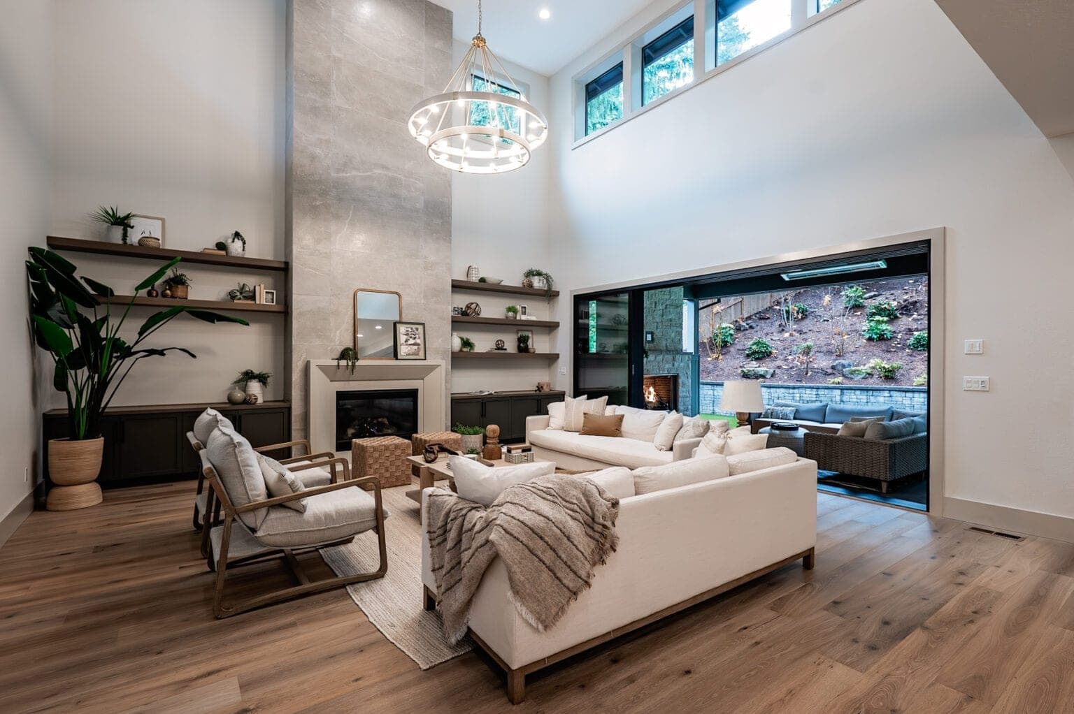 Modern great room with minimalist cast-stone fireplace surround, floor-to-ceiling shelving, and expansive glazing.