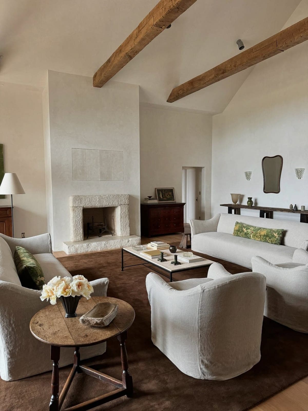 Clean-lined cream surround anchors a bright, minimalist living room with exposed timber beams and neutral furnishings.