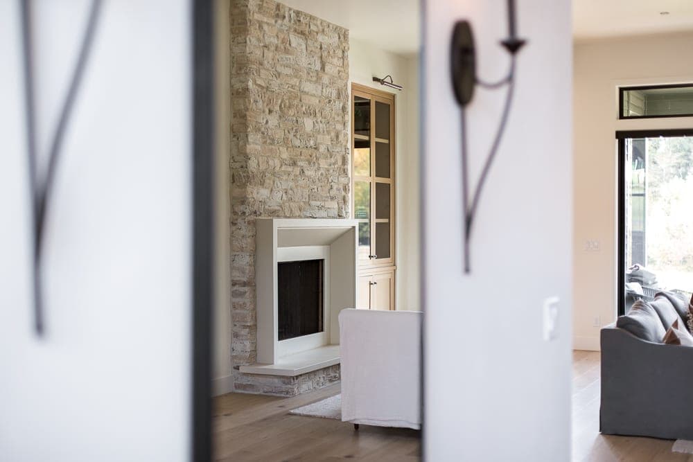 Minimalist cream cast-stone fireplace surround with clean lines anchors modern living space with stacked stone accent wall.