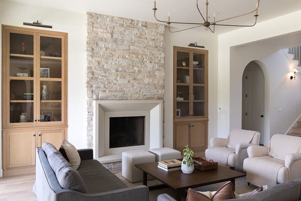 Clean-lined fireplace surround anchors bright, modern great room with natural stone accent wall and curated furnishings.