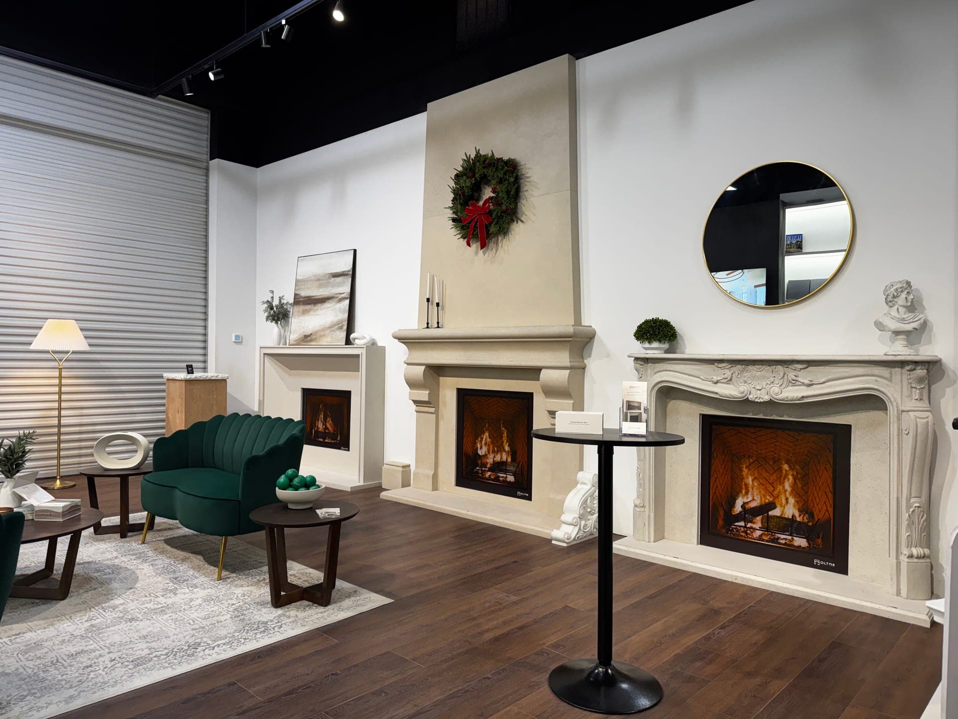 Three Oltre cast stone fireplace surrounds installed and lit on a showroom floor.