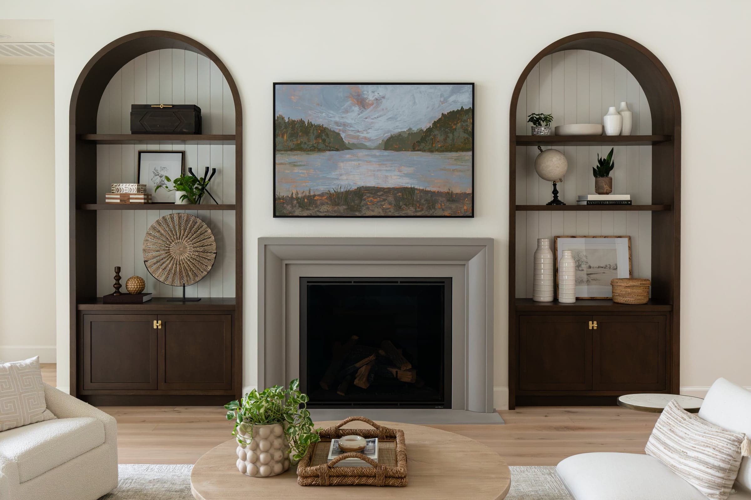 Stillwater Vista — Verona cast stone fireplace surround in Natural Stone, centered between arched walnut alcoves in a 20-foot vaulted great room.