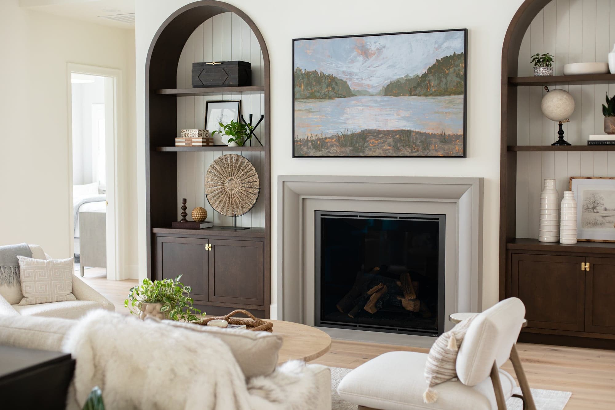 Stillwater Vista — Verona cast stone fireplace flanked by arched walnut display alcoves in the great room seating area.